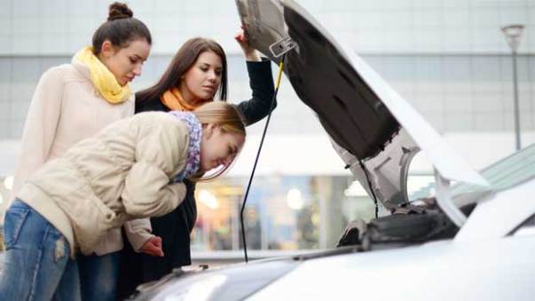 Friends looking under hood of car